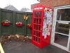 An image of a decorated, red telephone box and wall plant pots full of flowers at Hungerford Resource Centre