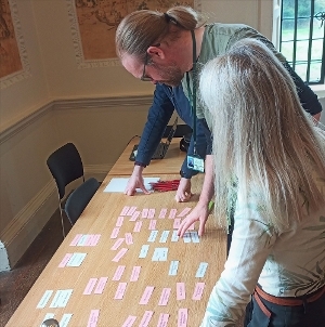 An photo of three people looking at coloured cards on a table at Shaw House