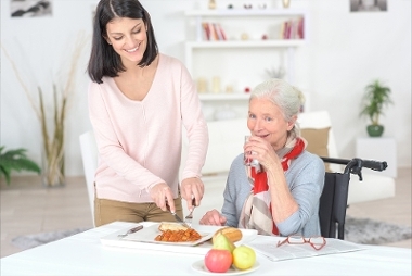 A young woman supporting elderly woman with preparing a meal.